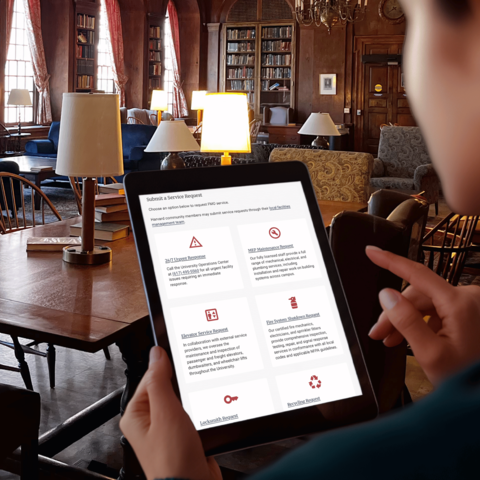 woman uses tablet displaying modern interface in historic Harvard library