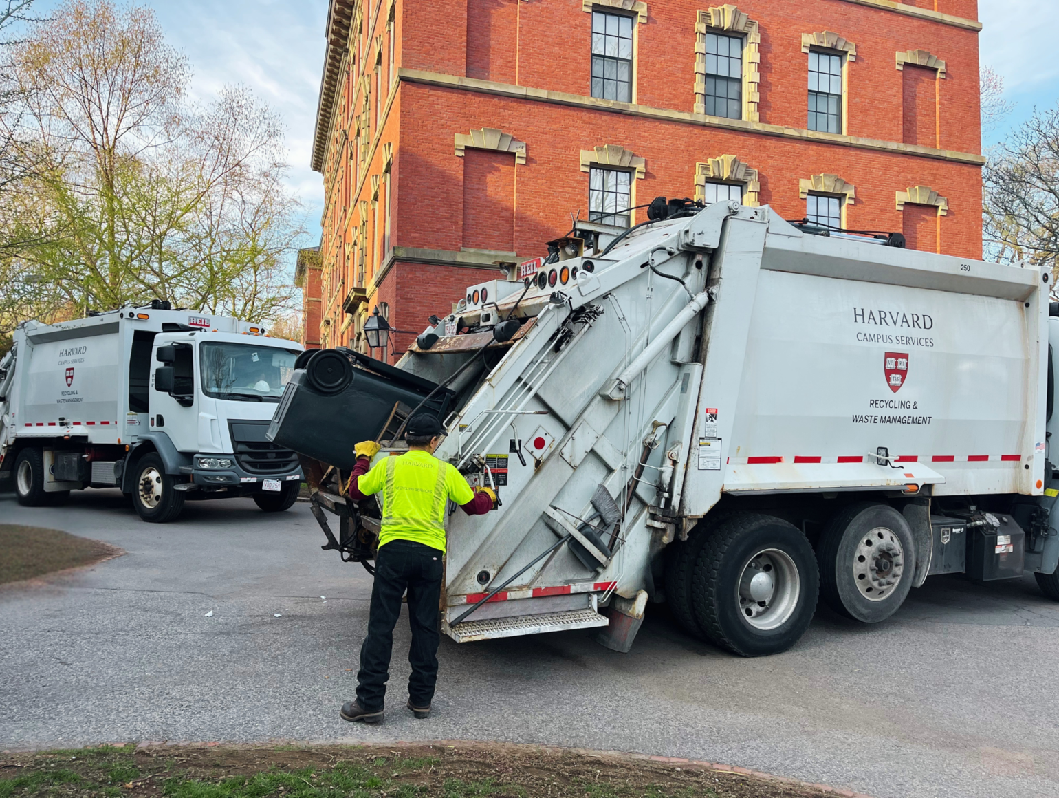A recycling employee emptying a container into a recycling truck
