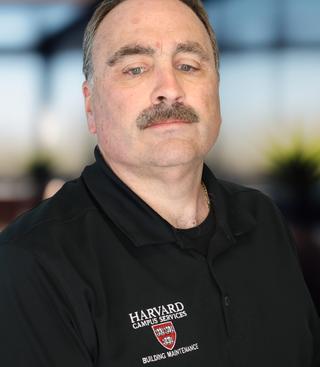A headshot of a man in a black polo