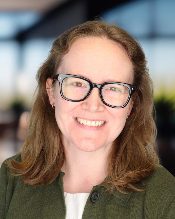 Headshot of a woman with reddish brown hair and glasses
