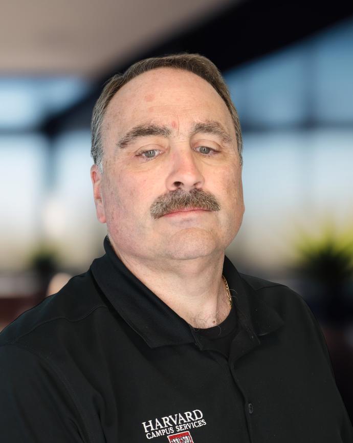 A headshot of a man in a black polo