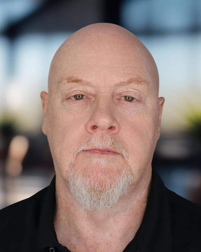 Headshot of a man in a dark polo shirt